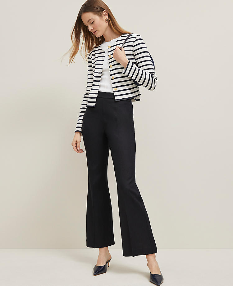 A woman wearing black flared ankle pants with a high waist, paired with a striped jacket and heels.