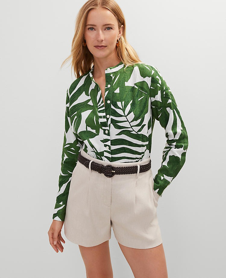 A woman wearing a green and white floral linen shirt with a point collar, button closures, long sleeves, and a shirttail hem.