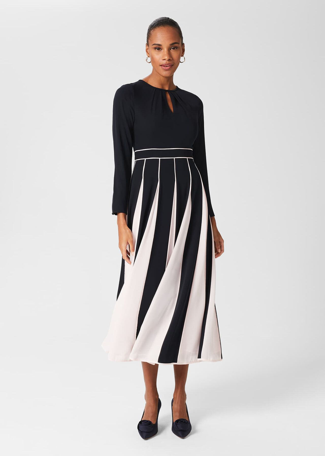 A woman wearing a black fit and flare midi dress with contrast chiffon pleats on the skirt, a keyhole front, and bracelet-length sleeves.