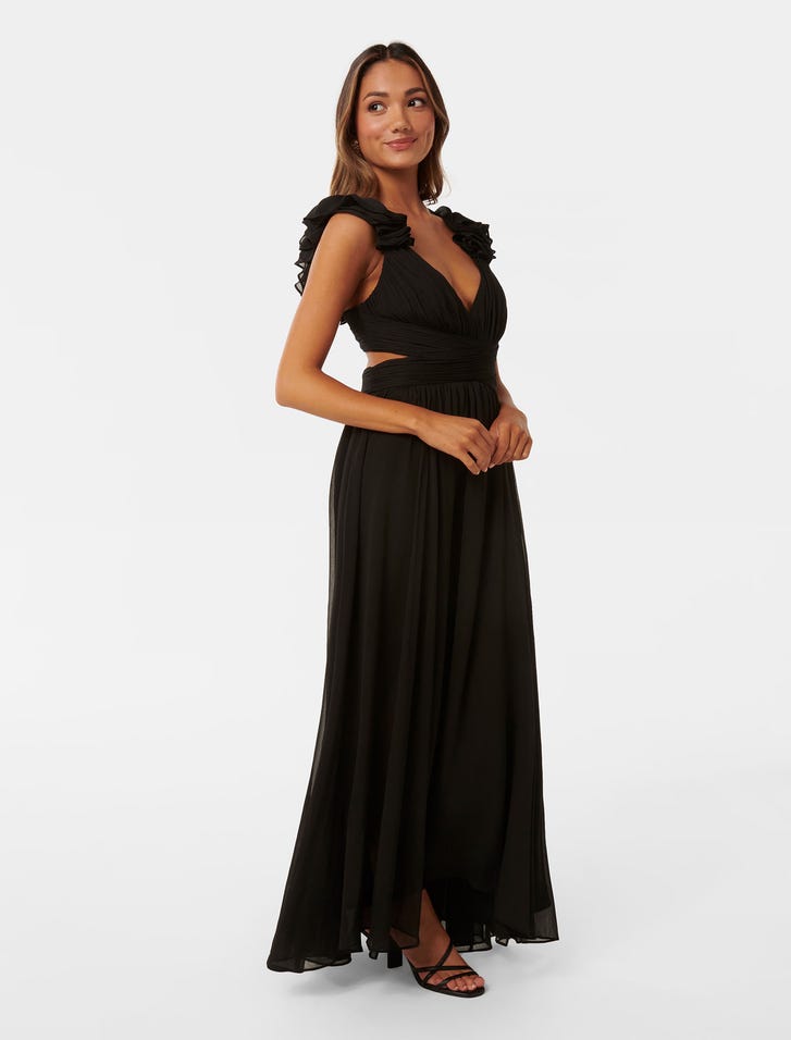 A woman wearing a black maxi dress with ruffle shoulder straps, a V-neckline, and a flowing skirt.