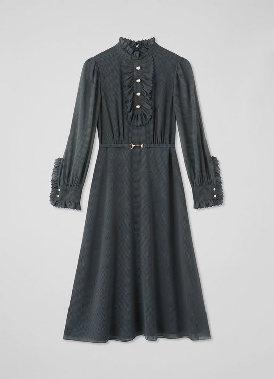 A women's midi dress in dark fabric with a houndstooth pattern, ruffled neckline and cuffs, pearl buttons, and a gold belt.