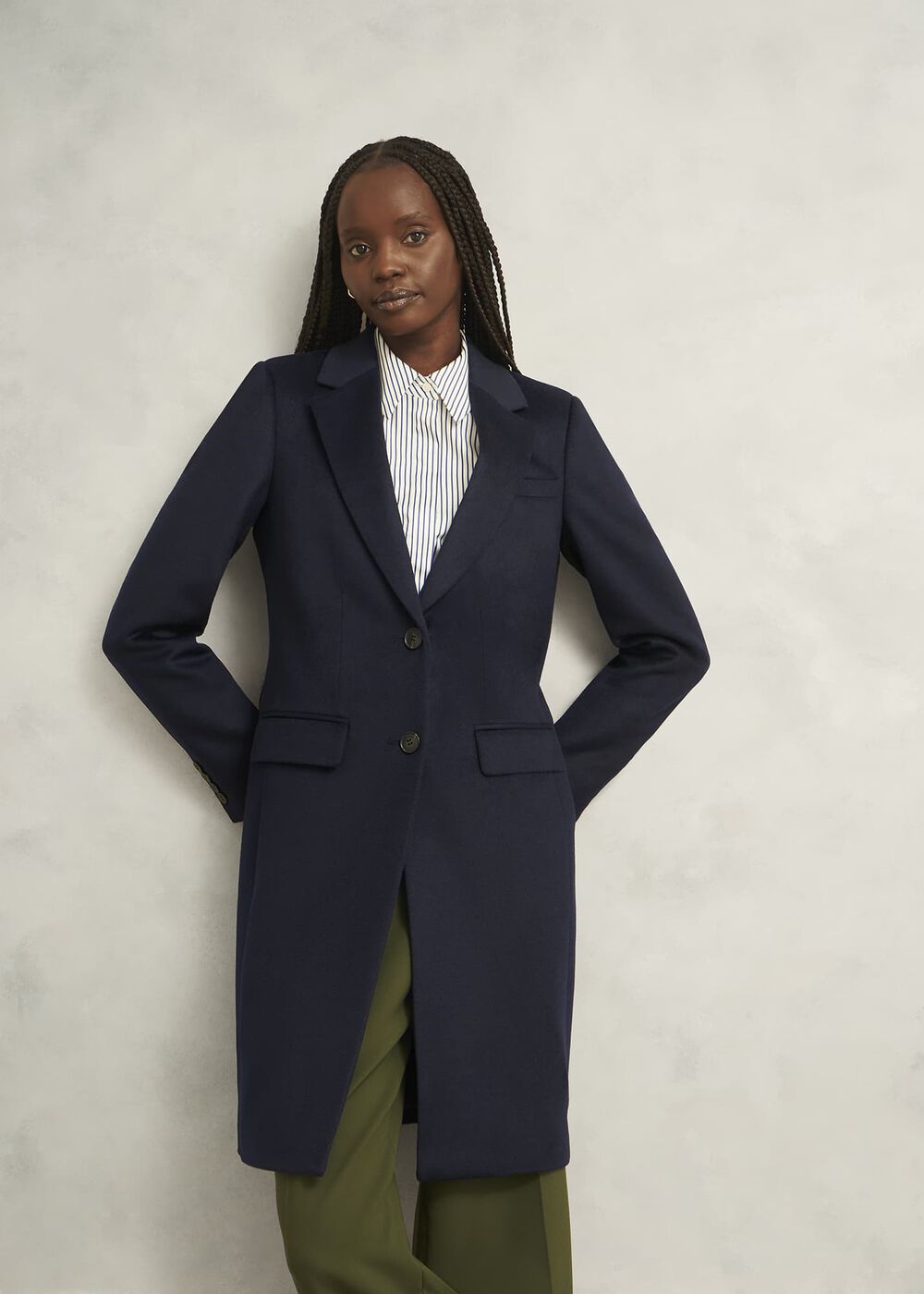 A woman wearing a navy blue tailored coat with a collared neckline, pockets, and a jacquard lining.