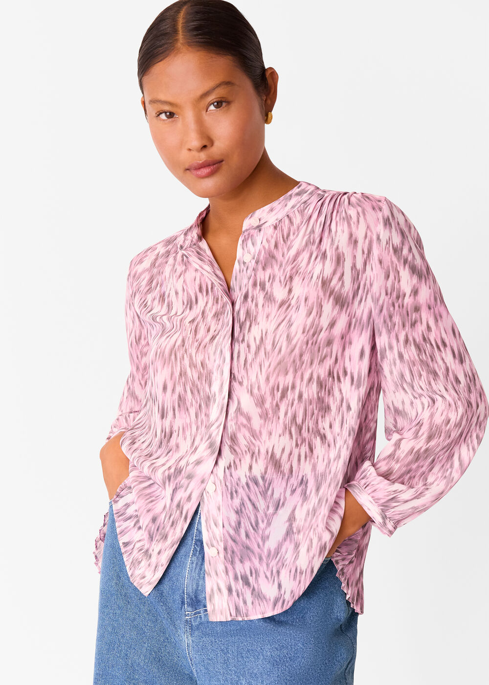 A woman wearing a pink and white leopard print shirt with pleats, a grandad collar, and long sleeves.