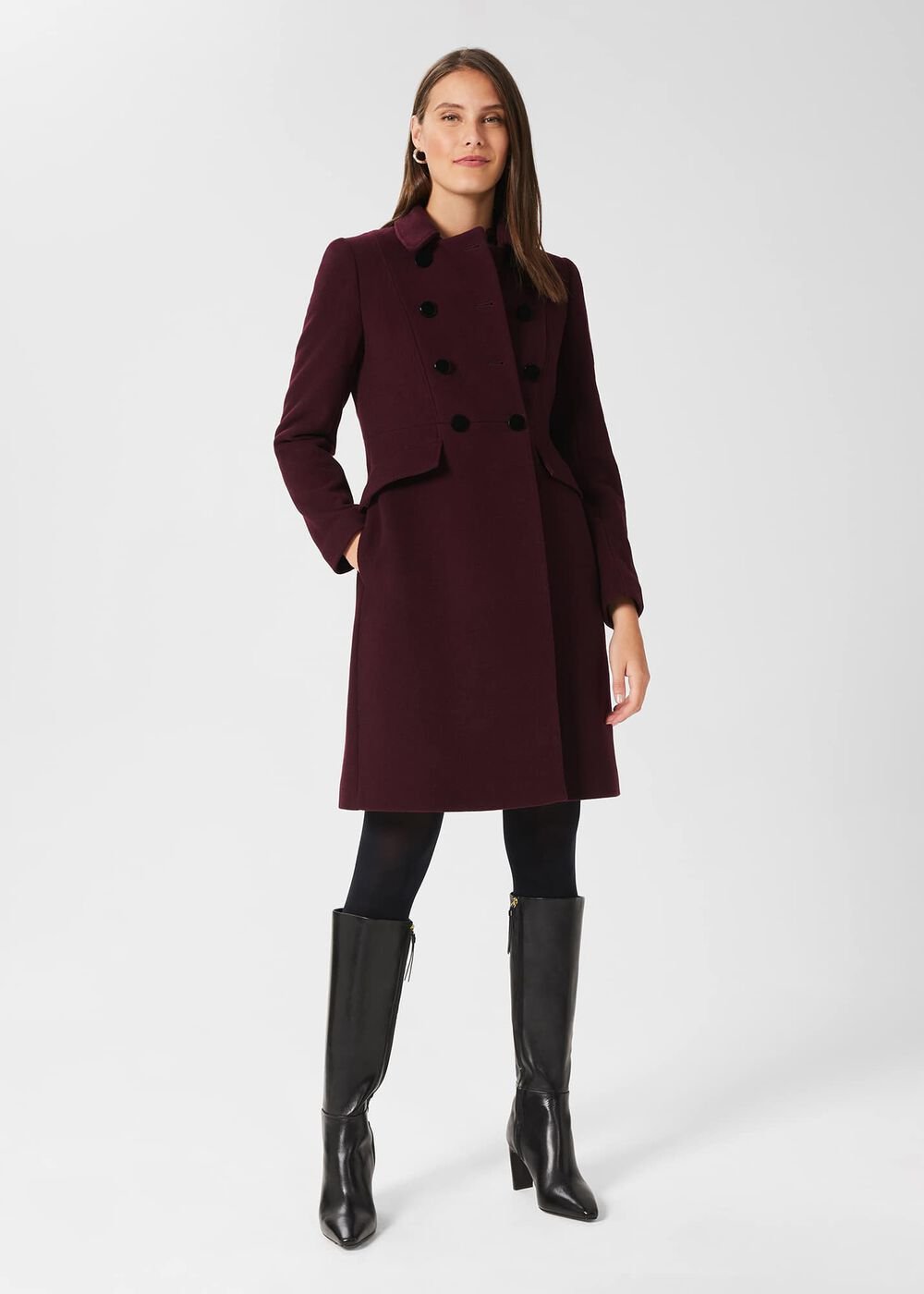 A woman wearing a deep burgundy wool blend coat with a double-breasted design, black buttons, collar neckline, and tailored fit, paired with black boots.