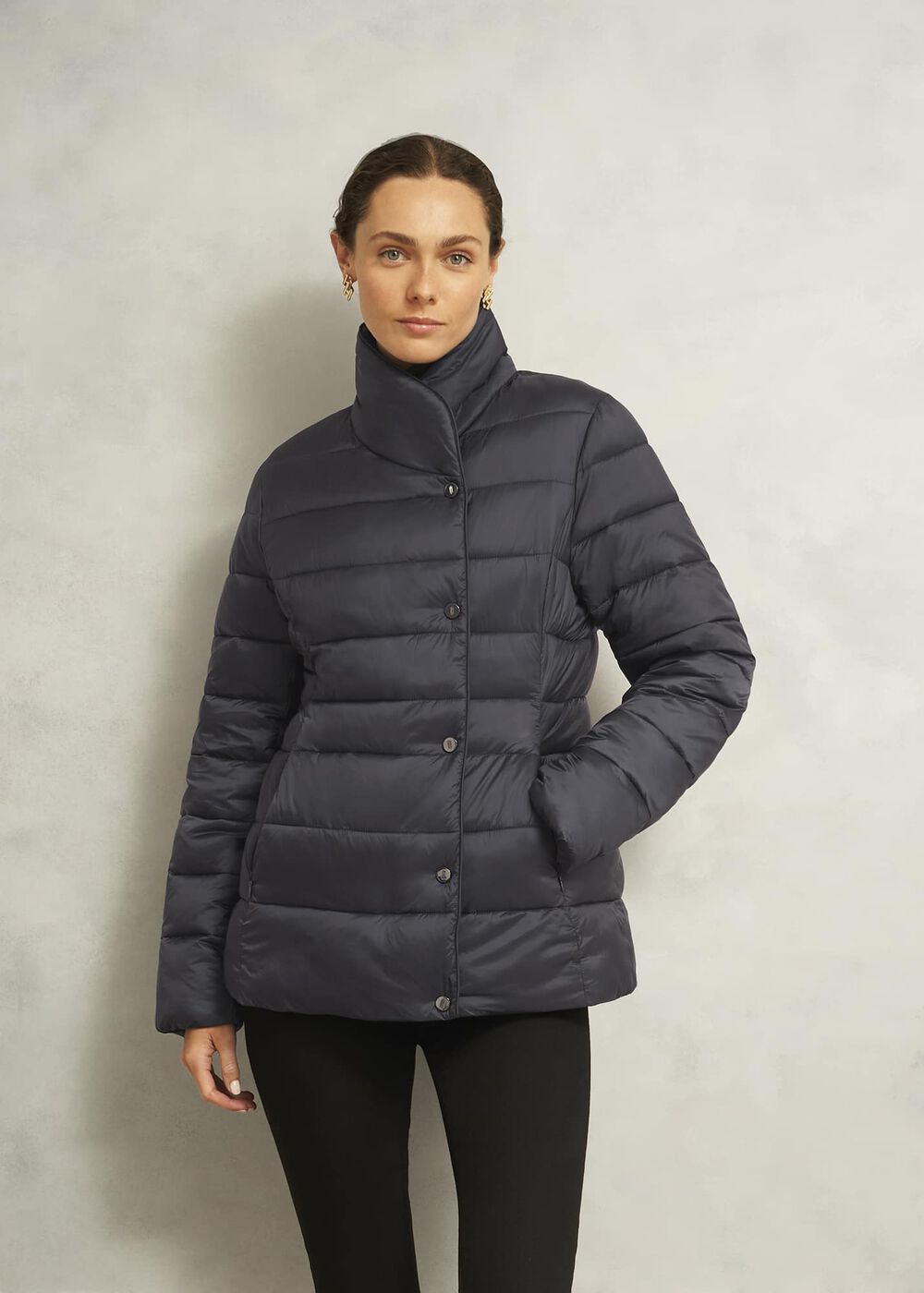 A woman wearing a dark navy puffer jacket with a funnel collar and fleece-lined pockets.