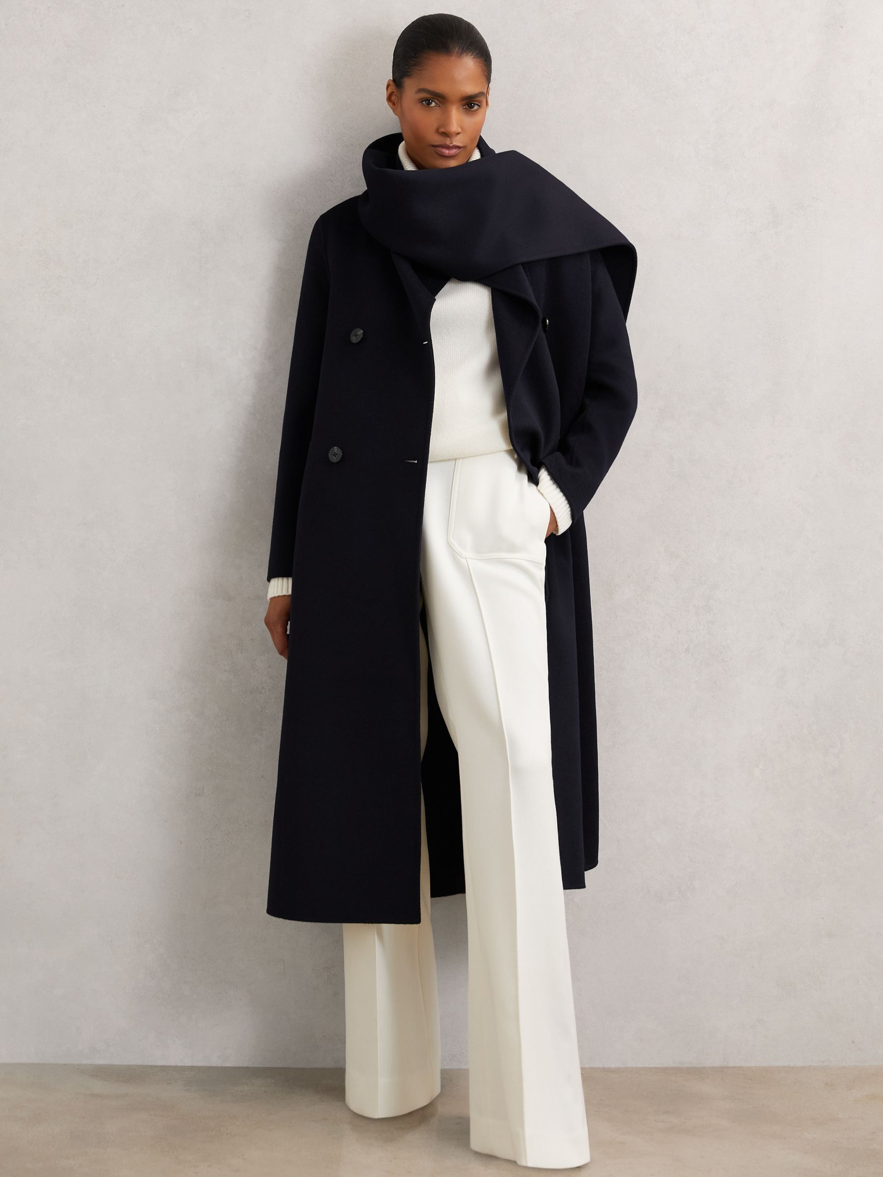 A woman wearing a navy wool-blend coat with a large scarf draped over her shoulders, double-breasted design, and no lining.
