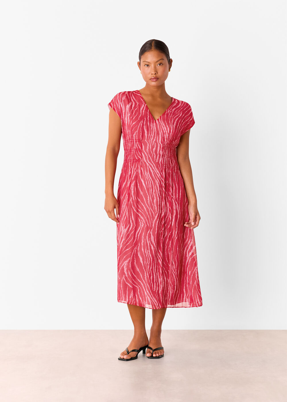 A woman wearing a red midi dress with a zebra pattern, V-neckline, short sleeves, and a fit-and-flare silhouette.