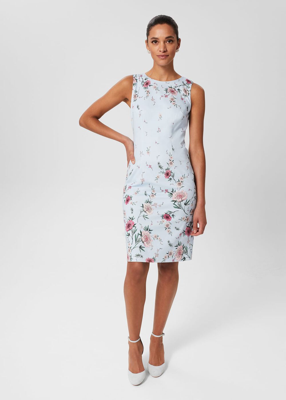 A woman wearing a sleeveless, light blue floral dress with pink and green floral patterns, crew neckline, and fitted silhouette.