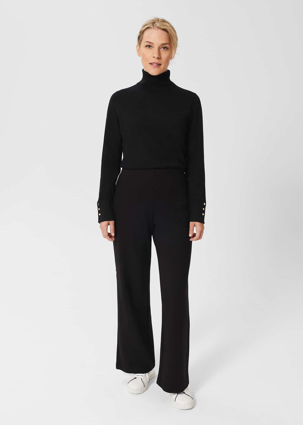 A woman wearing black wide-leg trousers with an elastic waistband, paired with a black turtleneck sweater.