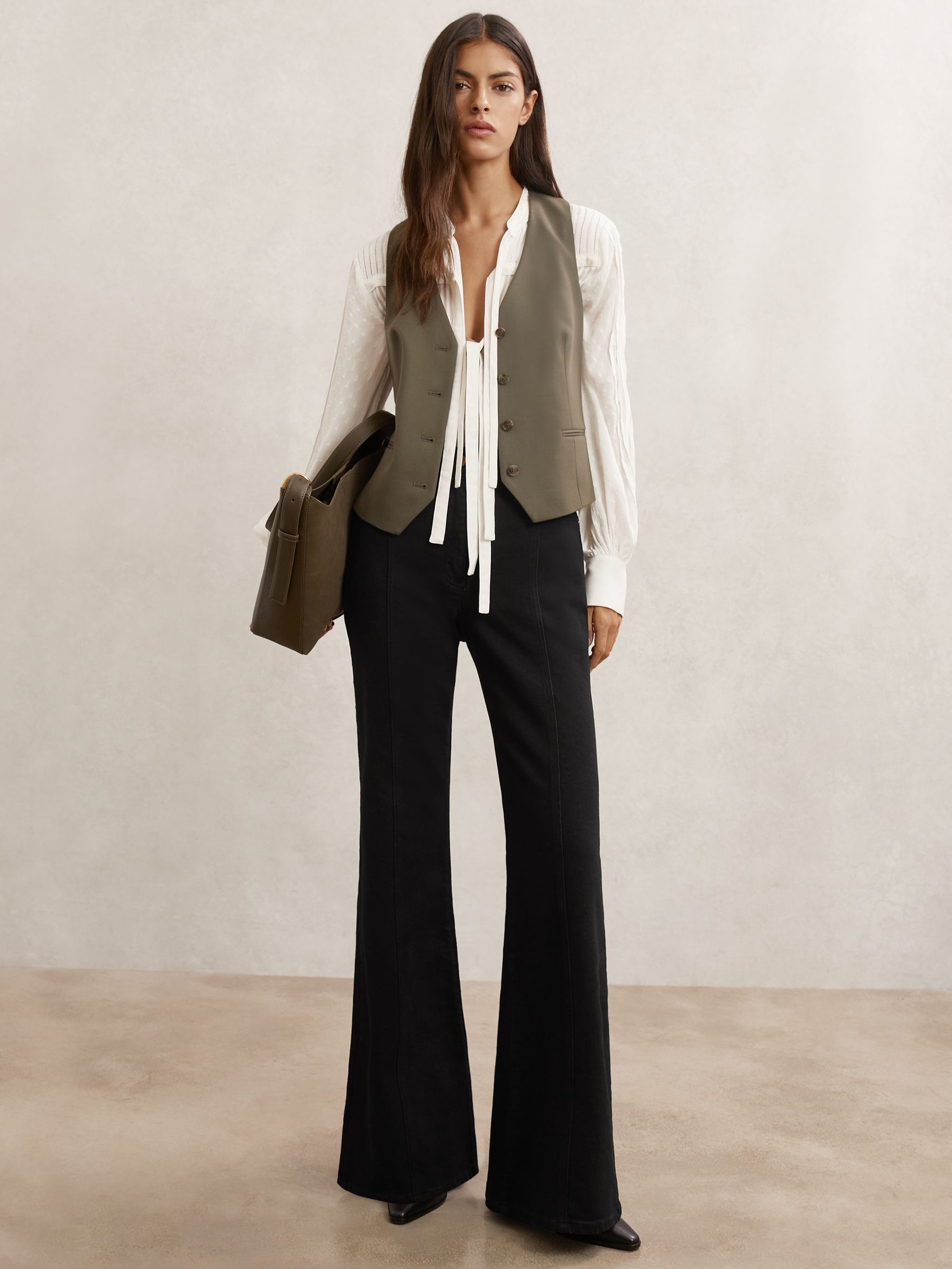 A pair of black flared jeans with seam detail, displayed on a model.