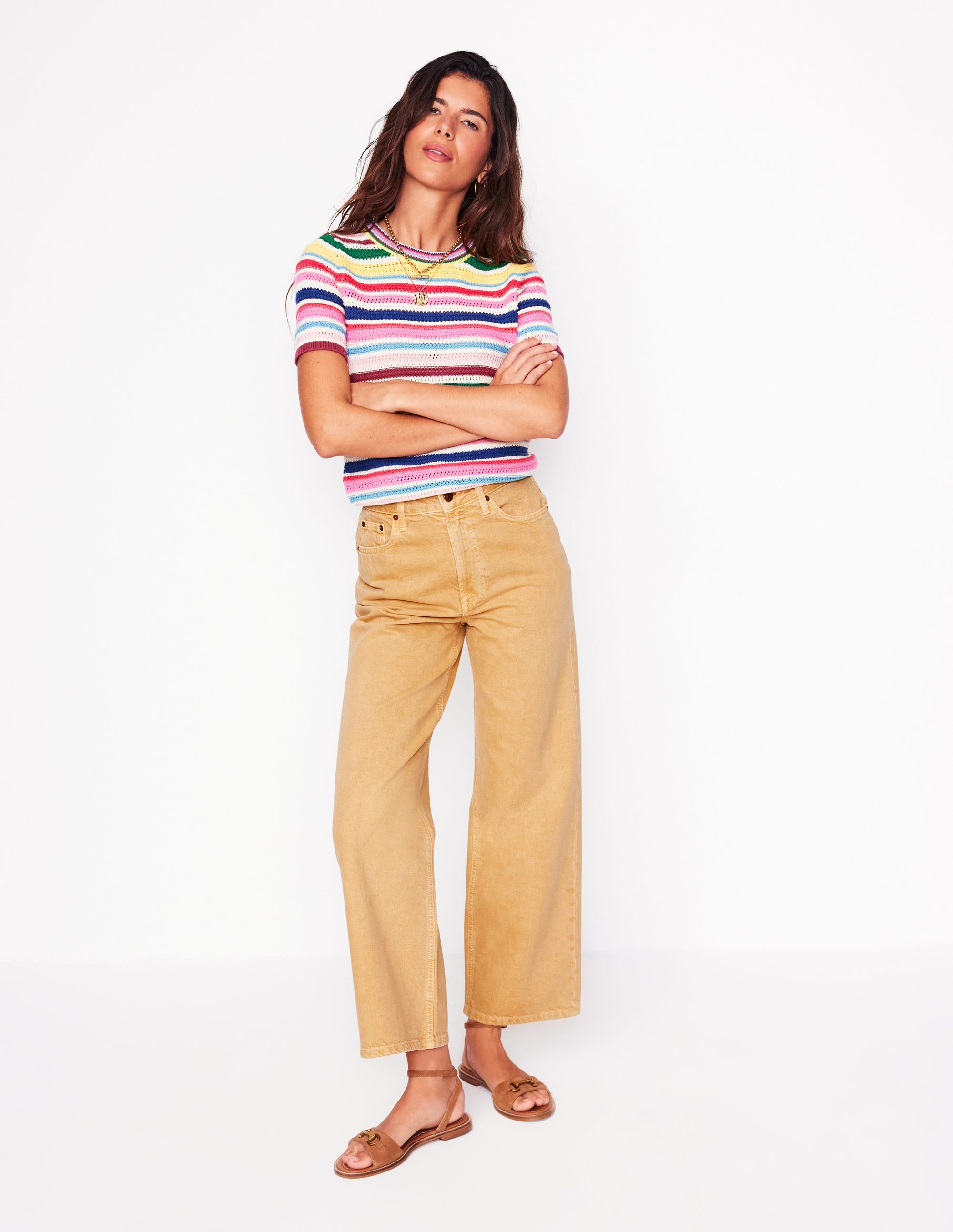 A woman wearing high-rise, straight-leg, cropped jeans in Buttermilk Yellow, paired with a colorful striped top.