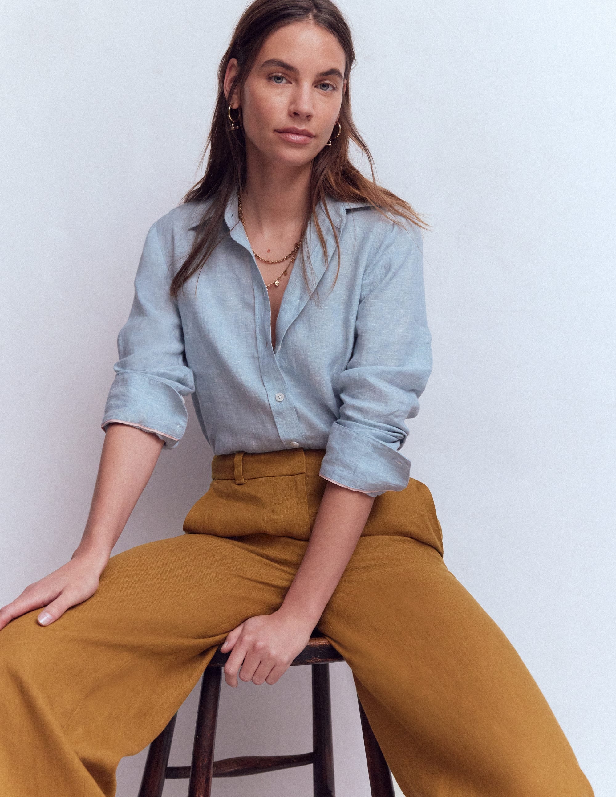 A pair of women's gingerbread-colored linen trousers with a wide-leg design, high waist, and functional pockets, made from lightweight fabric.