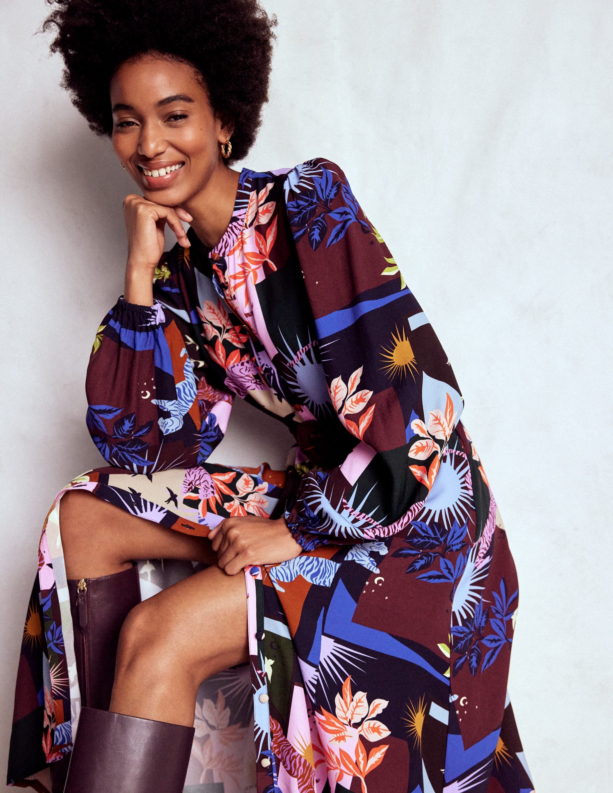 A woman wearing a long, multicolour shirt dress with a cosmic savanna print, featuring full sleeves, a tie belt, and pockets.