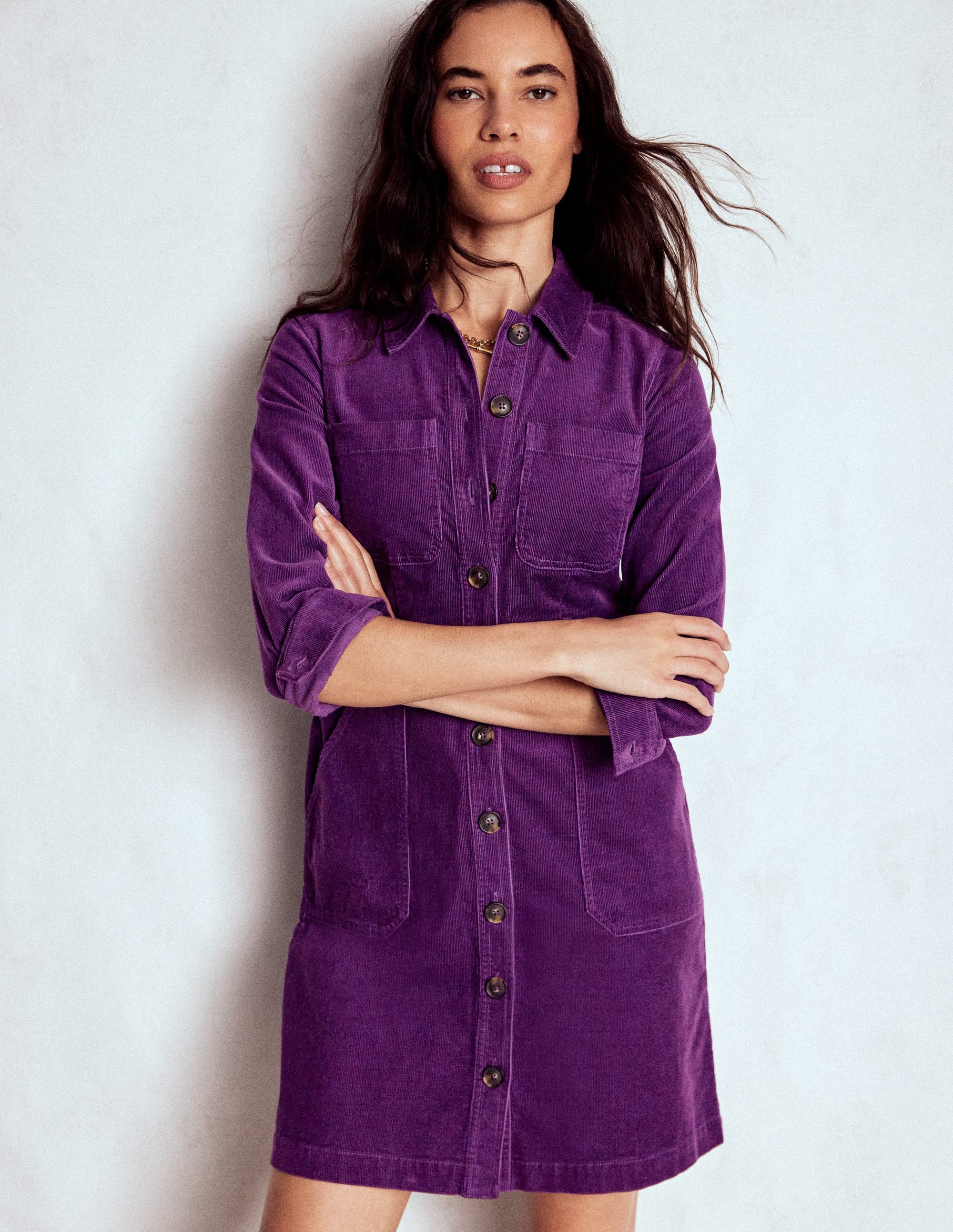 A woman wearing a Viola Purple short dress with utility pockets, button-down front, and rolled-up sleeves.