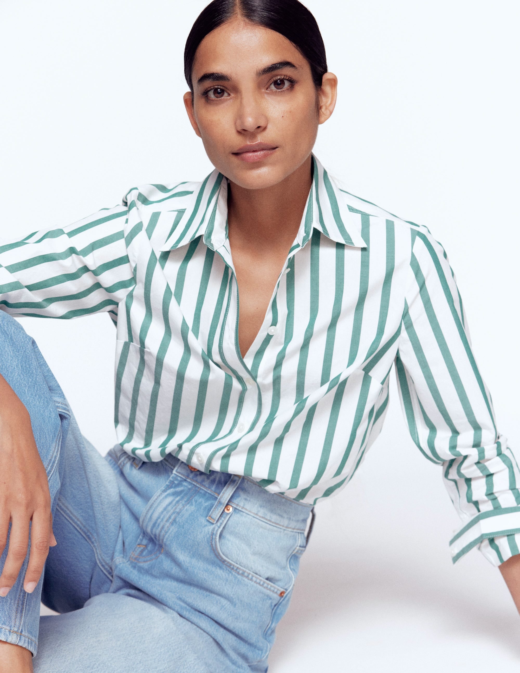 A woman wearing a green and ivory striped cotton shirt with a collar and long sleeves.
