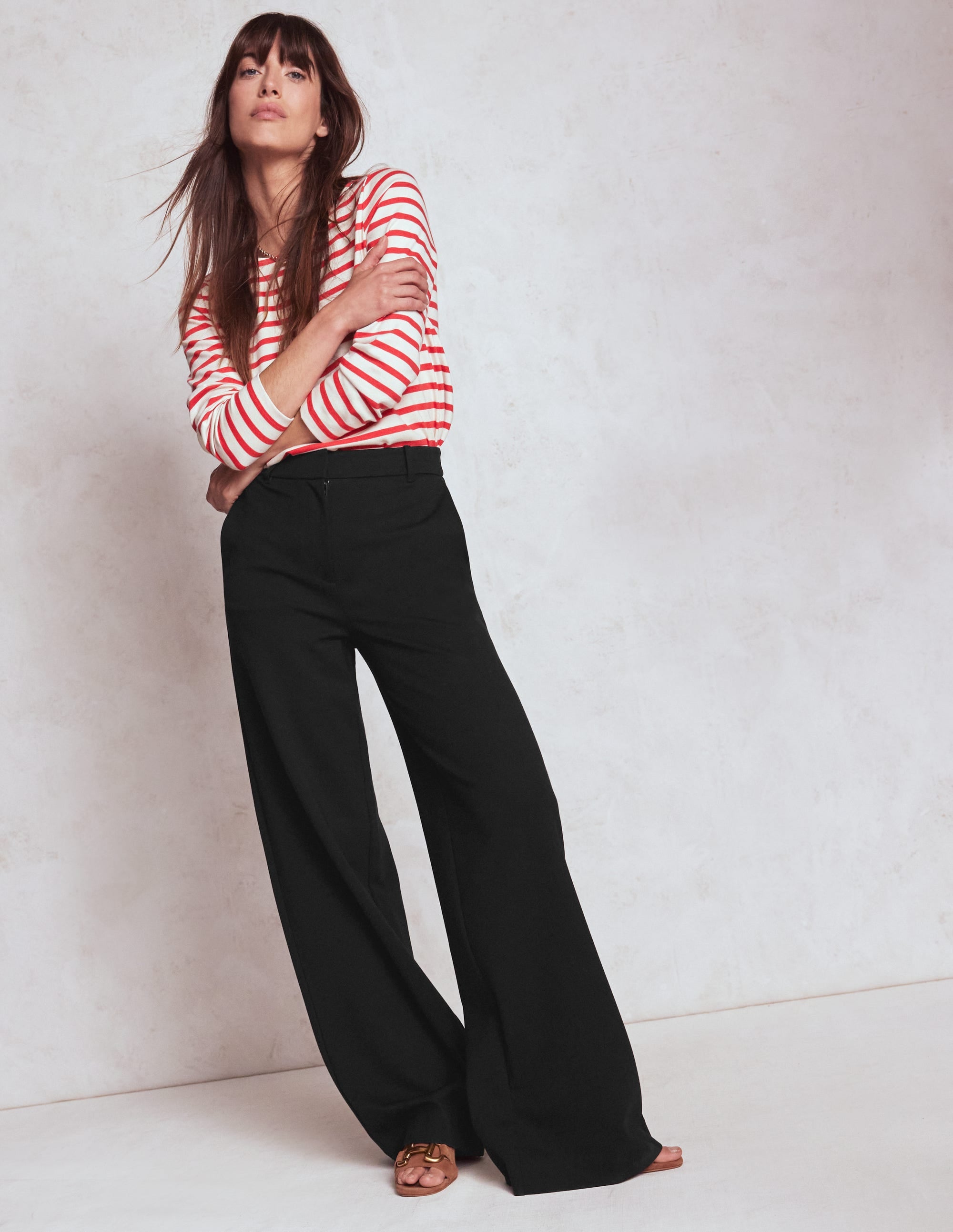 A woman wearing black Belgravia Ponte Trousers with a red and white striped top, standing against a plain background.